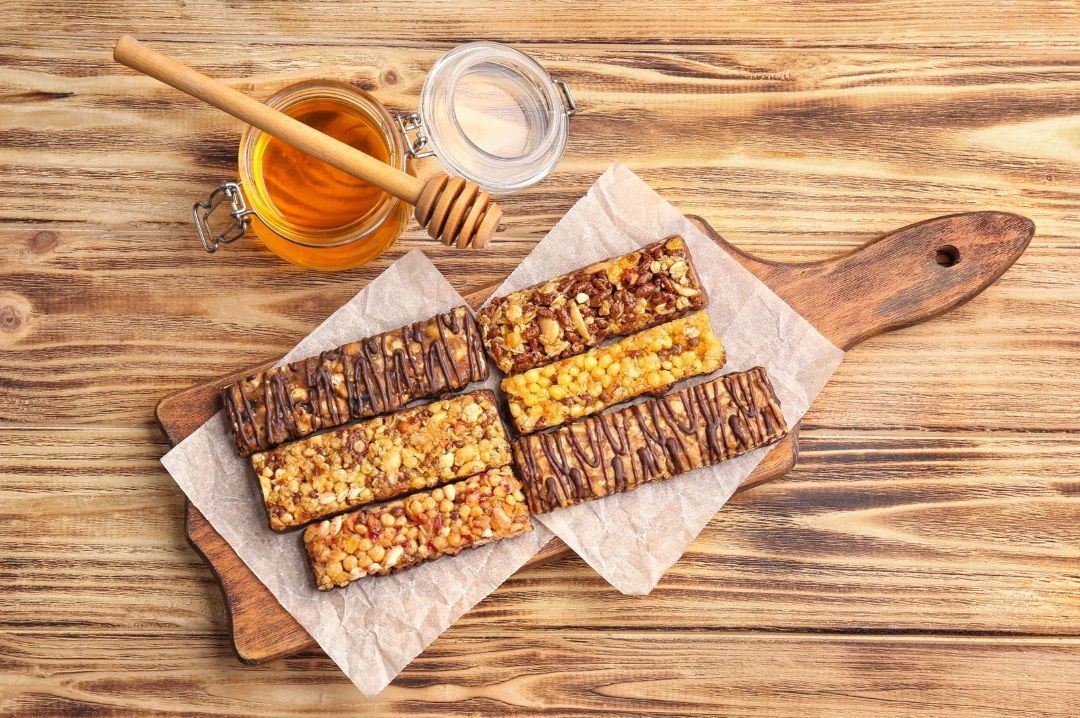 Tarro de miel y barrita energética sobre una mesa, como ejemplos de carbohidratos simples para reponer energía durante la escalada
