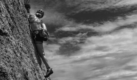 Escaladora en una pared vertical, simbolizando el esfuerzo físico y la importancia de la energía durante la actividad