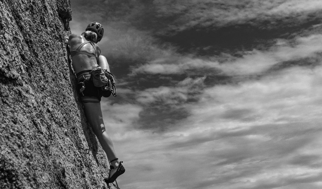 Escaladora en una pared vertical, simbolizando el esfuerzo físico y la importancia de la energía durante la actividad