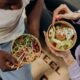 Dos personas comiendo con palillos, ejemplo de cómo comer despacio favorece una mejor digestión