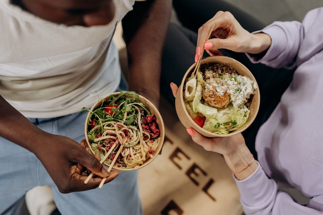 Dos personas comiendo con palillos, ejemplo de cómo comer despacio favorece una mejor digestión