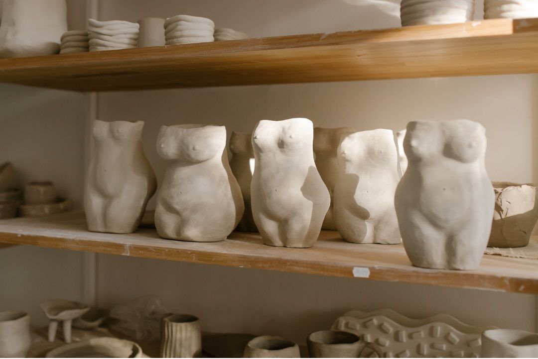 Cinco esculturas de barro que muestran torsos femeninos, representando distintas formas corporales.
