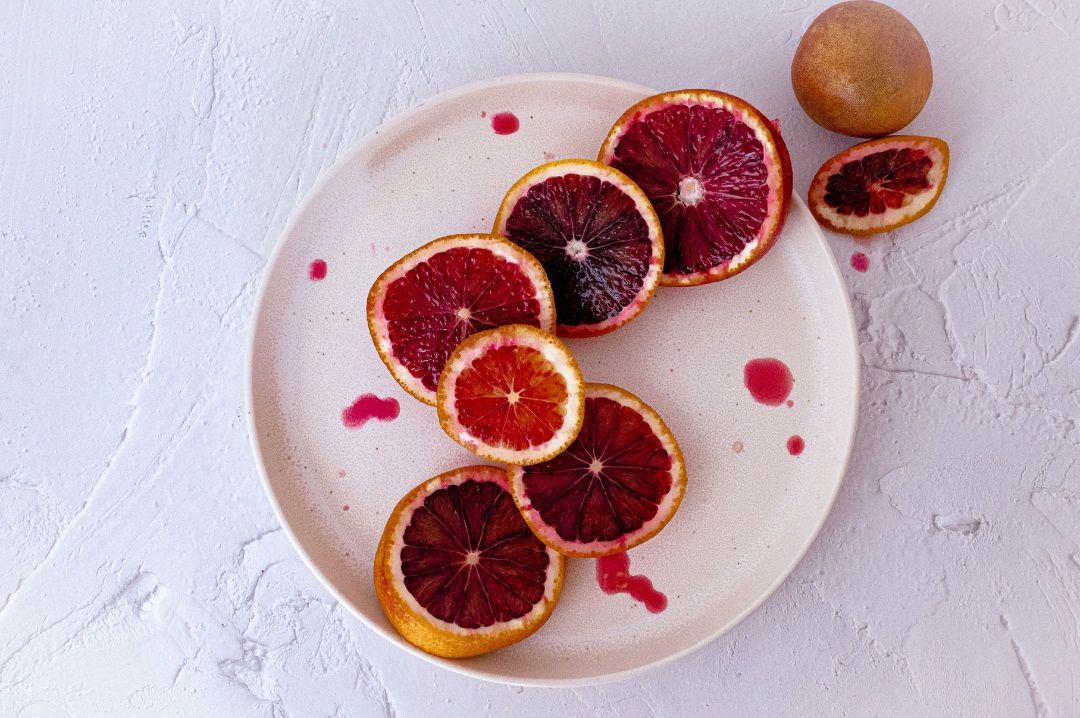 Rodajas de pomelo rojo en un plato, alimento rico en vitamina C y antioxidantes útil durante la fase menstrual